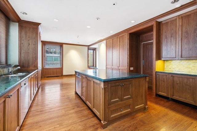 kitchen featuring dishwasher, sink, tasteful backsplash, a kitchen island, and light hardwood / wood-style flooring