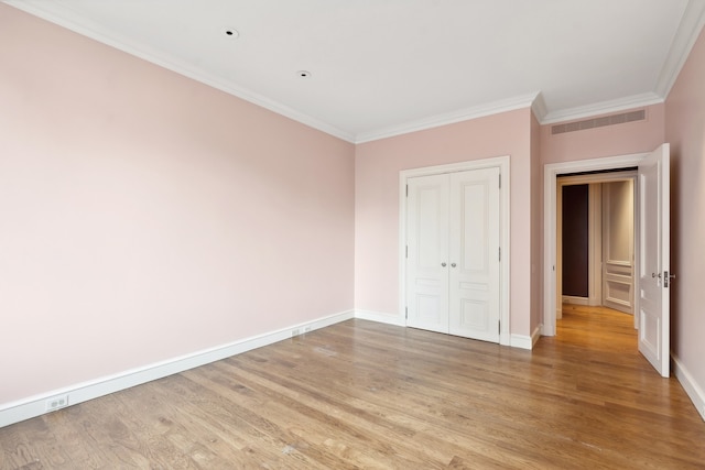 unfurnished bedroom with ornamental molding, light wood-type flooring, and a closet