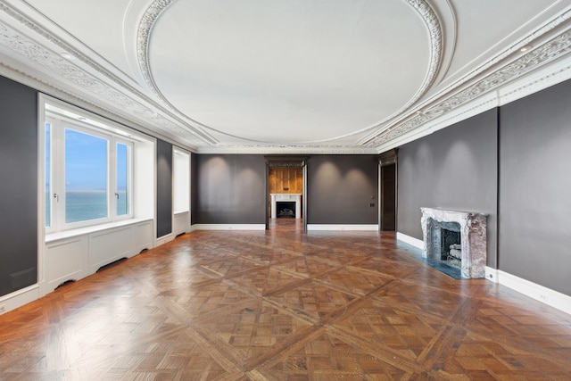 unfurnished living room featuring a premium fireplace, a water view, parquet flooring, and crown molding