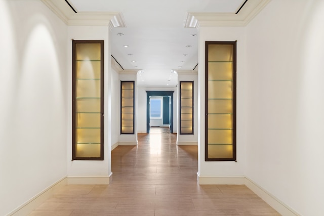 corridor with light wood-type flooring and crown molding