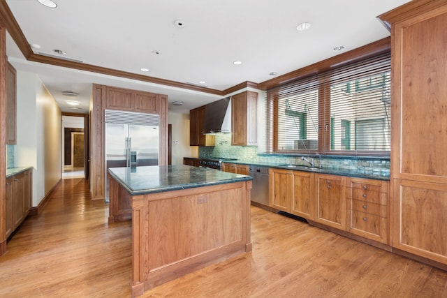 kitchen with wall chimney exhaust hood, light hardwood / wood-style floors, a kitchen island, and sink