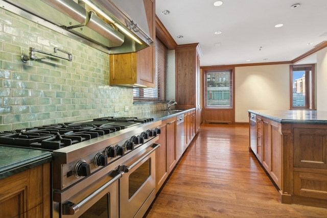 kitchen with a healthy amount of sunlight, light hardwood / wood-style flooring, appliances with stainless steel finishes, and tasteful backsplash