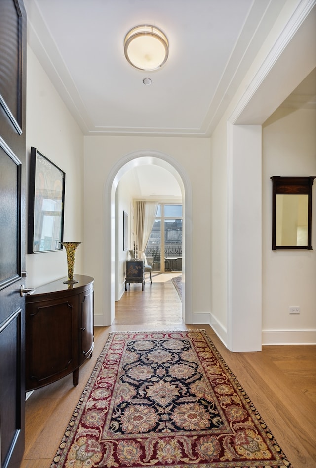 hallway with wood-type flooring and ornamental molding