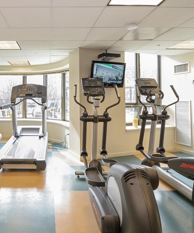 exercise room featuring a paneled ceiling and concrete floors