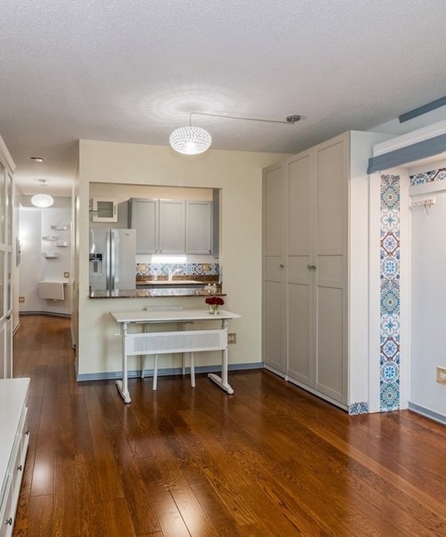 kitchen featuring stainless steel fridge with ice dispenser, dark hardwood / wood-style floors, and a textured ceiling