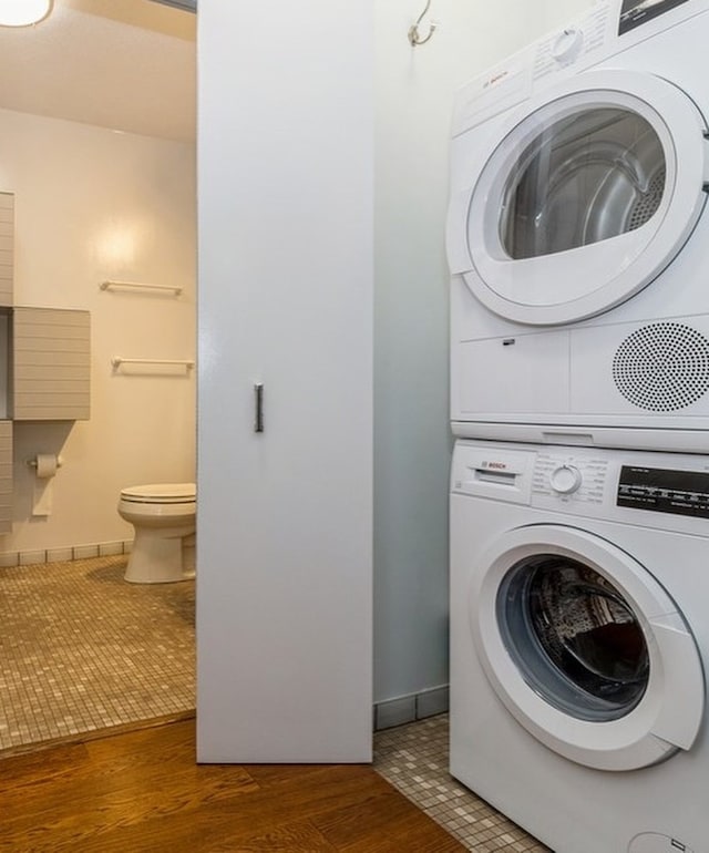 washroom with stacked washing maching and dryer and dark hardwood / wood-style floors