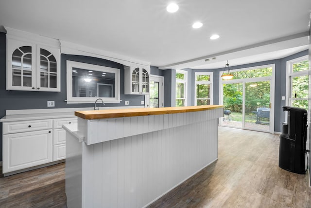 kitchen with white cabinets, dark wood-type flooring, a center island, and wood counters