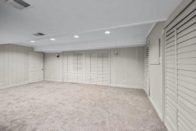 basement featuring wood walls and light carpet