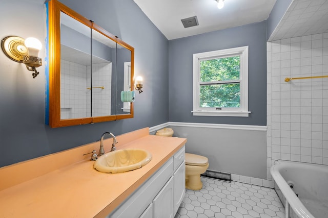 full bathroom with tile patterned flooring, vanity, tiled shower / bath combo, and toilet