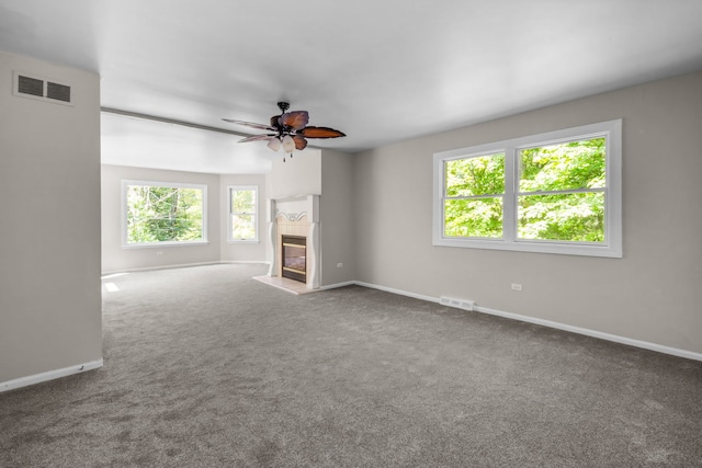 unfurnished living room with a wealth of natural light, carpet flooring, and ceiling fan