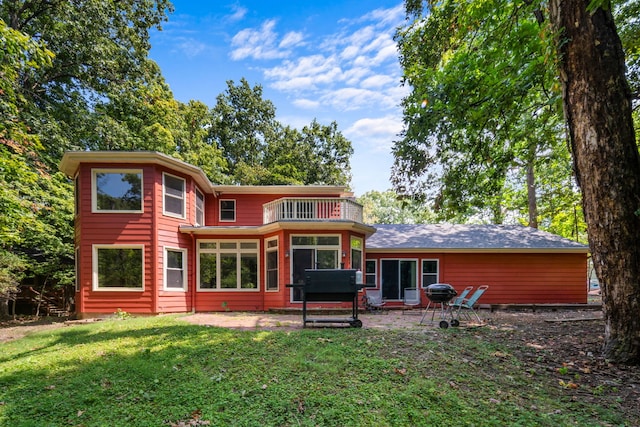 back of property featuring a balcony, a yard, and a patio area