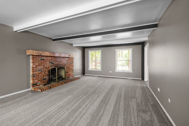 unfurnished living room with beamed ceiling, carpet, and a brick fireplace