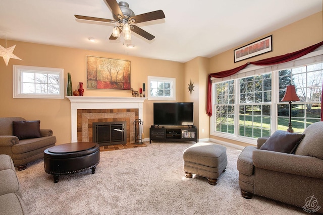 carpeted living room featuring a tiled fireplace and ceiling fan