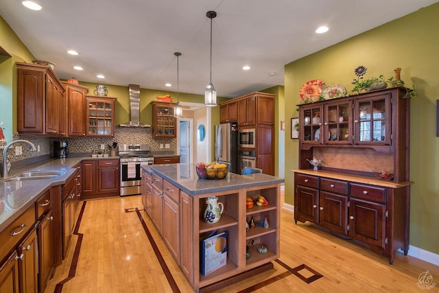 kitchen with sink, wall chimney exhaust hood, stainless steel appliances, light hardwood / wood-style floors, and a kitchen island