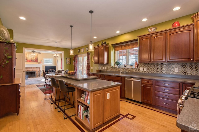 kitchen featuring dishwasher, a center island, backsplash, ceiling fan, and decorative light fixtures