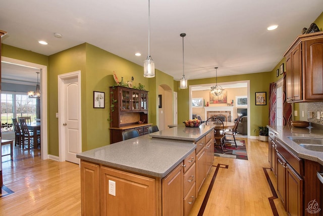 kitchen with pendant lighting, a kitchen island, an inviting chandelier, and light hardwood / wood-style flooring