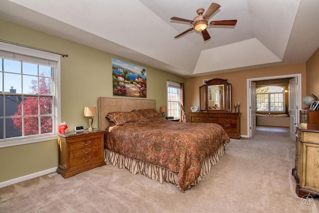 carpeted bedroom featuring ceiling fan and a raised ceiling