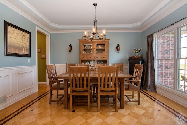 dining space featuring light parquet flooring, crown molding, and a chandelier