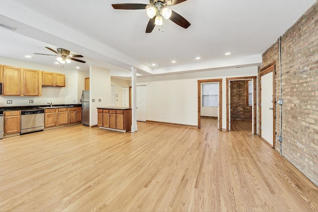 kitchen with sink, brick wall, appliances with stainless steel finishes, ceiling fan, and light wood-type flooring