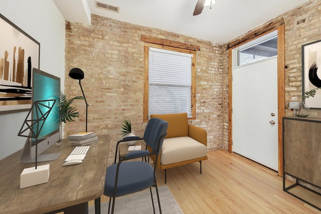 office area featuring ceiling fan, light hardwood / wood-style floors, and brick wall