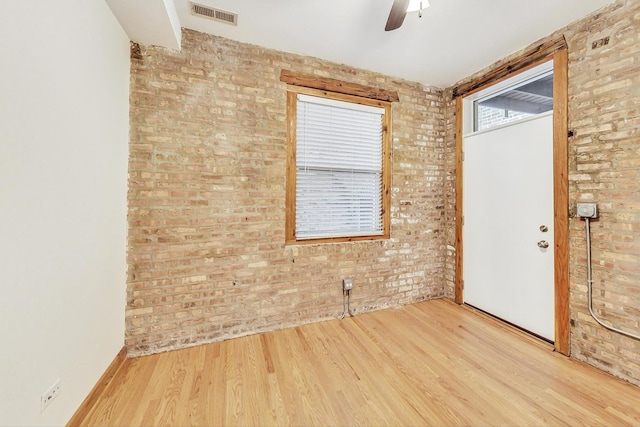 unfurnished room with ceiling fan, brick wall, and light hardwood / wood-style flooring