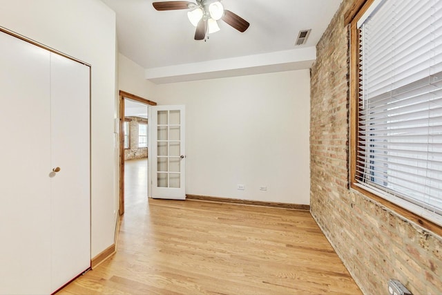 unfurnished bedroom with ceiling fan, multiple windows, and light wood-type flooring