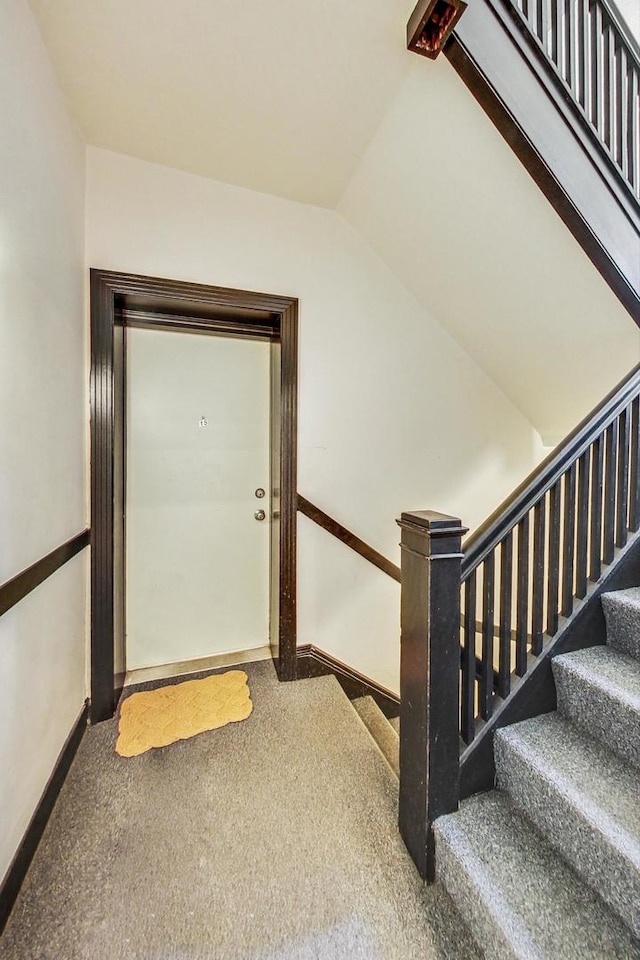 staircase featuring lofted ceiling and carpet