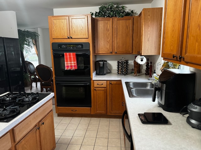 kitchen featuring light tile patterned flooring, sink, and black appliances