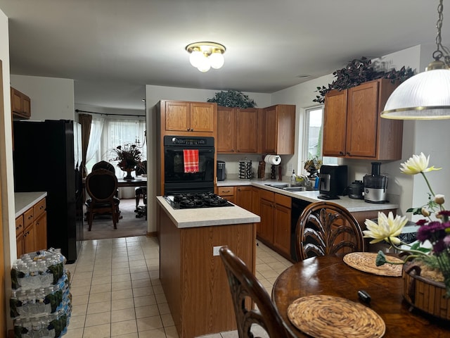 kitchen featuring black appliances, light tile patterned floors, pendant lighting, sink, and a center island