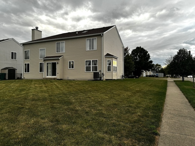 back of property featuring central AC unit and a yard