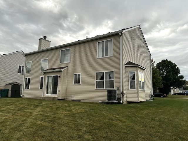 rear view of property with a lawn and central AC