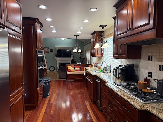 kitchen with dark hardwood / wood-style flooring, tasteful backsplash, stainless steel appliances, sink, and hanging light fixtures