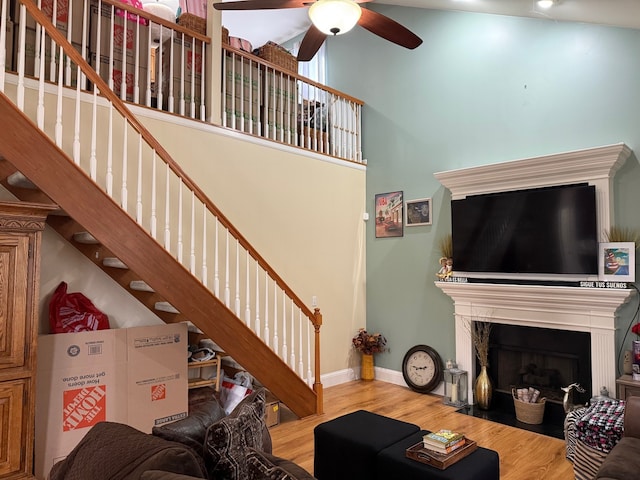 living room featuring a fireplace, a high ceiling, hardwood / wood-style flooring, and ceiling fan