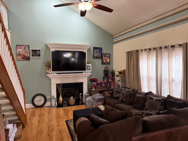 living room with ceiling fan, light hardwood / wood-style floors, lofted ceiling, and a fireplace