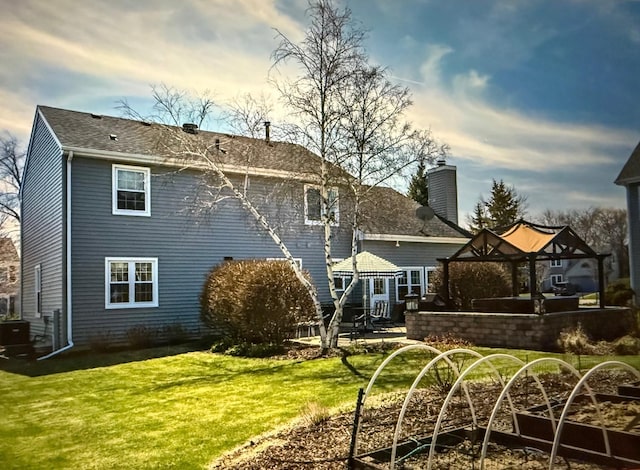 back of property featuring a gazebo and a lawn