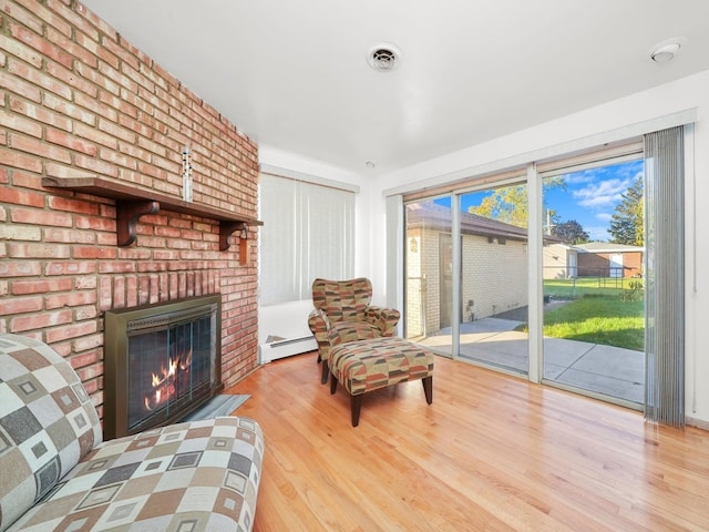 sitting room with a fireplace, a baseboard radiator, and light hardwood / wood-style flooring