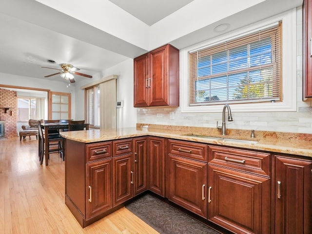 kitchen with tasteful backsplash, kitchen peninsula, sink, and light hardwood / wood-style floors