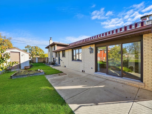 rear view of property featuring a patio area, a lawn, and a shed