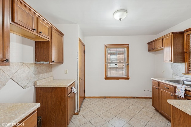 1242 E 98th St, Chicago, IL 60628 - kitchen with brown cabinets, decorative backsplash, light countertops, baseboards, and light tile patterned floors