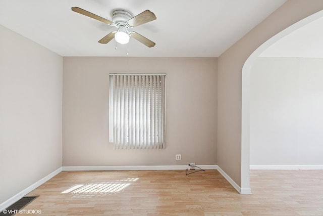 1242 E 98th St, Chicago, IL 60628 - empty room with arched walkways, light wood finished floors, ceiling fan, and baseboards