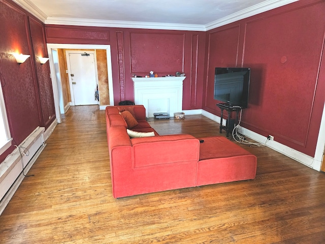 living room featuring wood-type flooring, baseboard heating, and ornamental molding