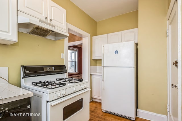 kitchen featuring white cabinets, tile counters, and white appliances