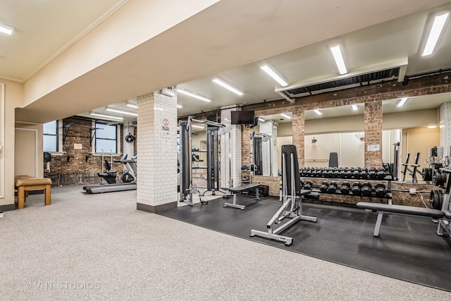 workout area with carpet flooring, ornate columns, and brick wall