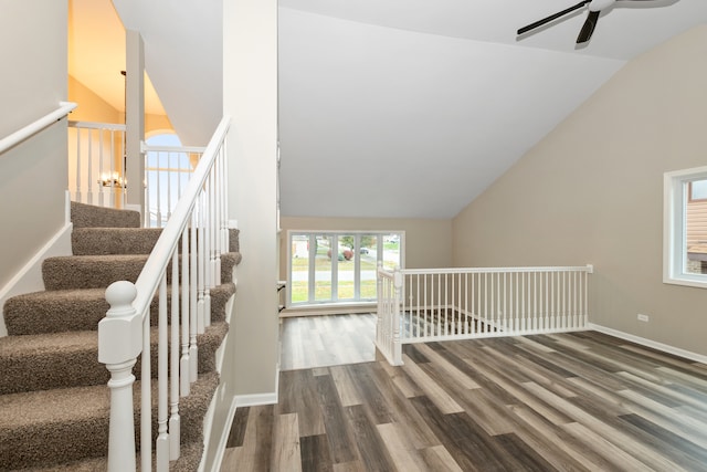 staircase featuring hardwood / wood-style floors, ceiling fan with notable chandelier, and high vaulted ceiling