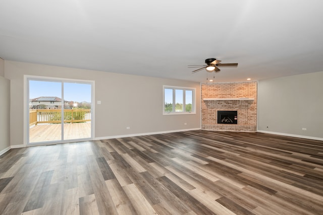 unfurnished living room featuring a fireplace, wood-type flooring, plenty of natural light, and ceiling fan