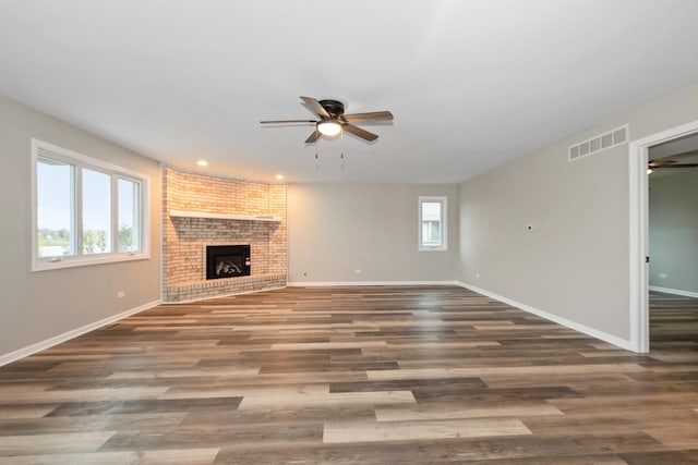 unfurnished living room with visible vents, plenty of natural light, a fireplace, and ceiling fan