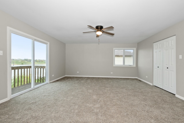 carpeted spare room with a water view and ceiling fan