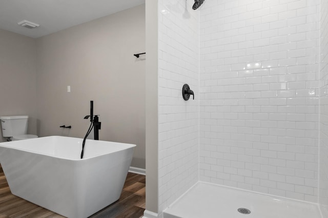 full bath with wood finished floors, visible vents, tiled shower, a freestanding tub, and toilet