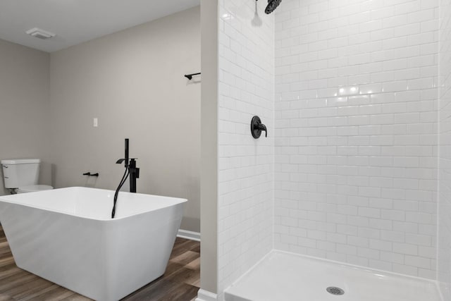 full bath with a tile shower, visible vents, toilet, and wood finished floors