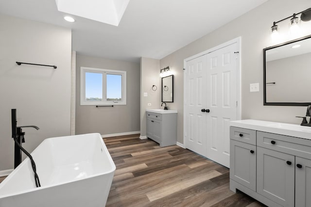 bathroom featuring a sink, wood finished floors, and a skylight